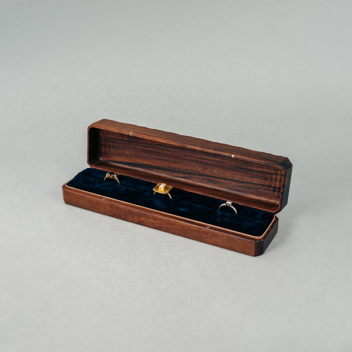 Open Jewellery Box made of walnut wood with three rings placed inside.
