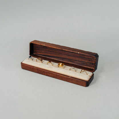 Open Jewellery Box made of walnut wood while The interior of the box is lined with soft velvet with six rings placed inside.