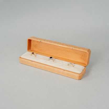 Open Jewellery Box made of beech wood while The interior of the box is lined with soft velvet with three rings placed inside.