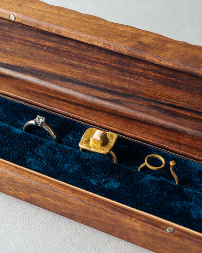 Close up of an open Jewellery Box made of walnut wood and the interior of the box is lined with soft velvet with thee rings placed inside.